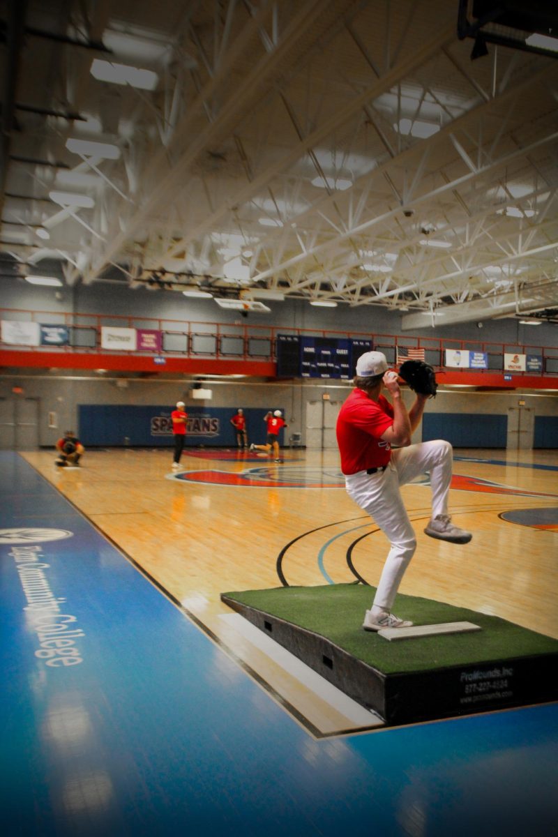 Pitcher Caleb Williams raises his leg before delivering a pitch during a practice at the Elgin Community College Fitness Center on March 23, 2026. Williams practiced his pitching mechanics atop the mobile mound as he gears for the remainder of the season. 