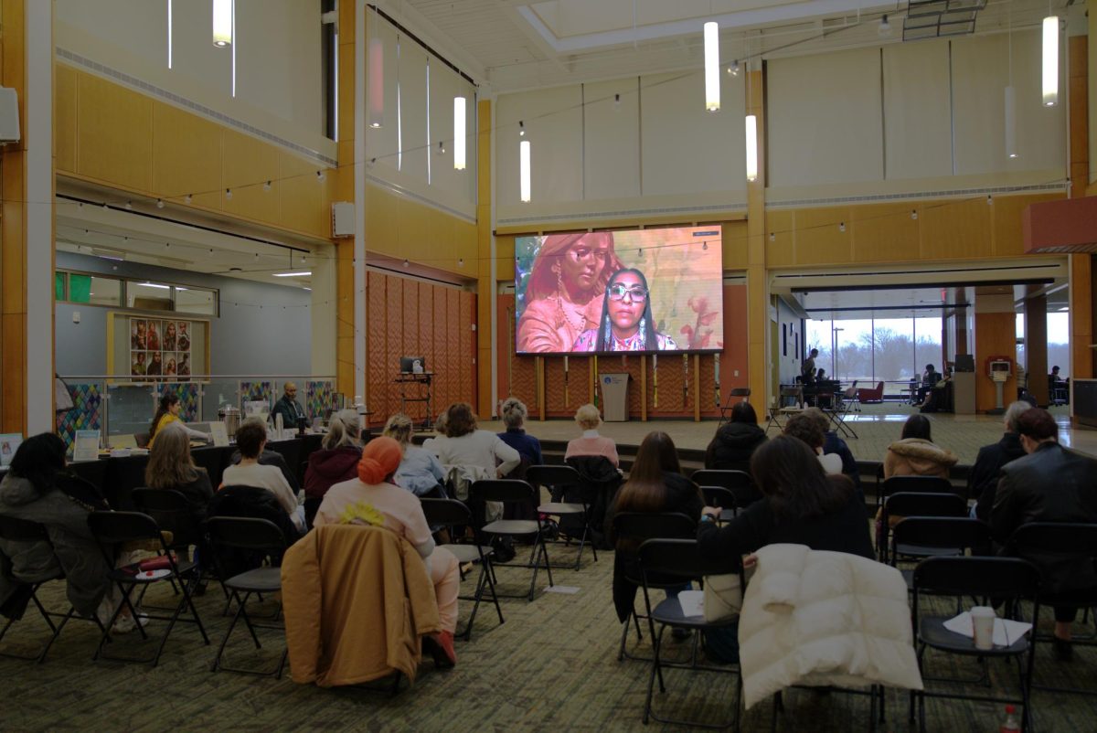 Small crowd in watching speaker on screen.