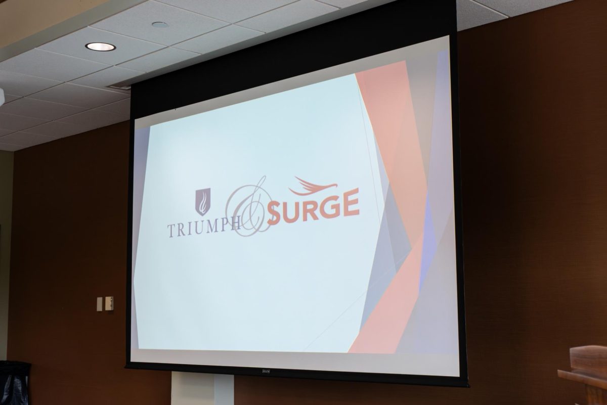 A projector displays ECC's Triumph and Surge logo during a meeting led by Erik Enders on April 27, 2026. This program is one of many that provides mentorship, academic support, and resources for students to stay enrolled and accomplish their goals.