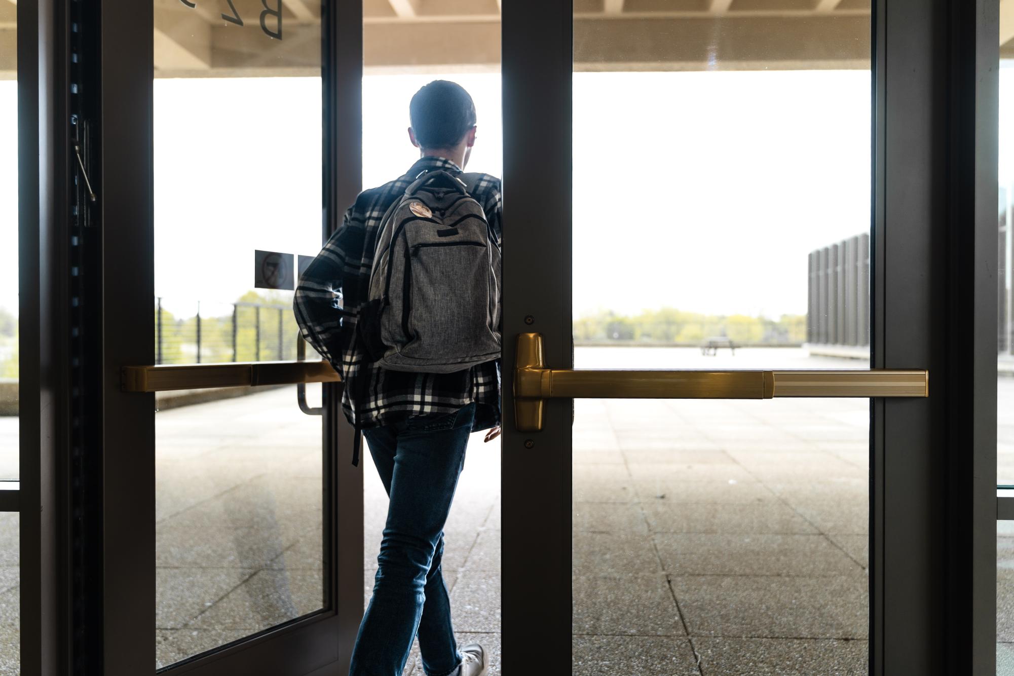 A student exits the second-level Building B doors, which doesn't have an ADA (Americans with Disabilities Act) button for disabled students, on May 6, 2026. Some doors throughout campus don't have ADA buttons installed, making it more difficult for students with physical disabilities to get to and from locations efficiently.